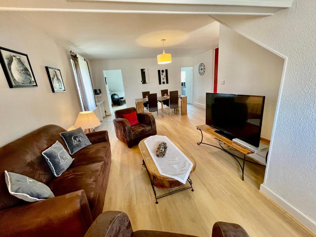 un salon avec un canapé et une télévision à écran plat dans l'établissement L'Ourson, à Gérardmer
