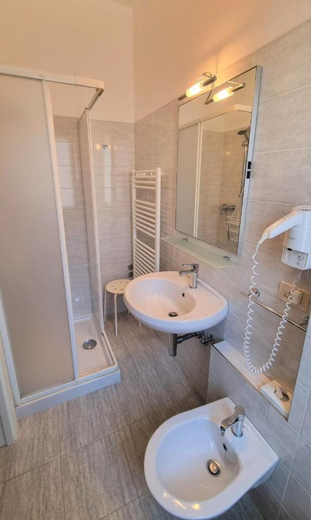 une salle de bain avec un lavabo blanc et une douche dans l'établissement Hotel Canoa, à Cervia