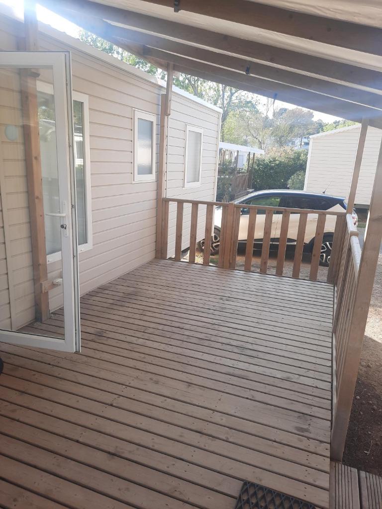 une terrasse couverte avec une terrasse en bois et une porte coulissante en verre. dans l'établissement Mobil-home premium 325, à Narbonne