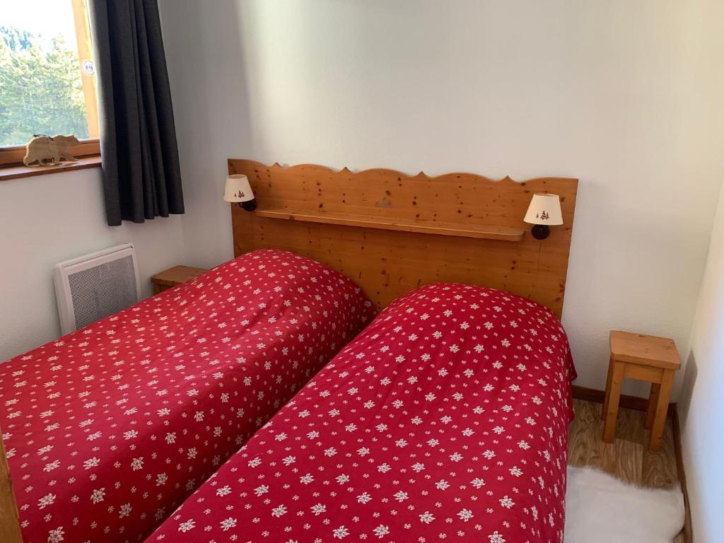 - une chambre avec 2 lits et des couettes rouges dans l'établissement Appartement Chamrousse, à Chamrousse