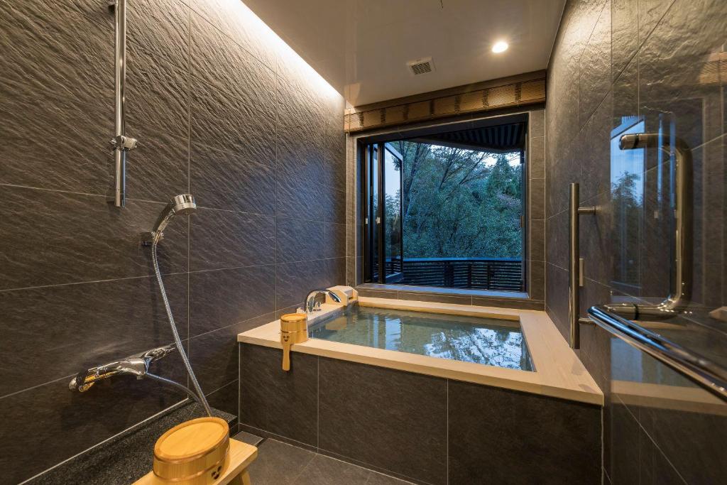 La salle de bains est pourvue d'une baignoire, d'une douche et d'une fenêtre. dans l'établissement Kinzan, à Kobe