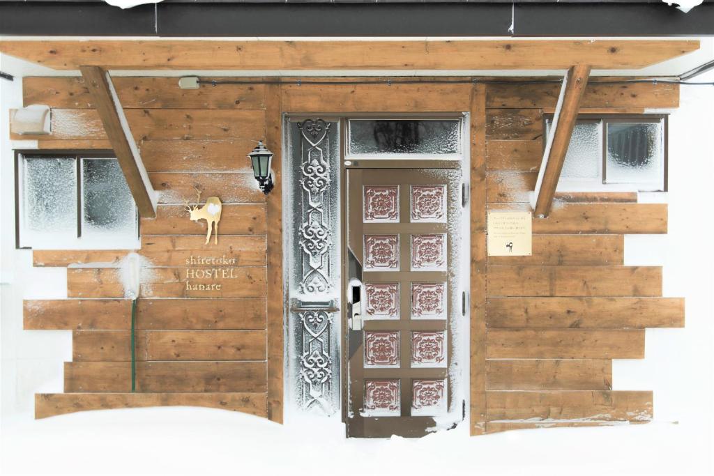 d'une porte d'un bâtiment en bois avec un panneau. dans l'établissement Shiretoko Village, à Shari