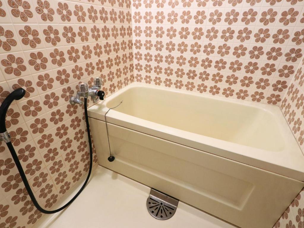 La salle de bains est pourvue d'une baignoire et de carrelage rose. dans l'établissement Suzunami, à Toba