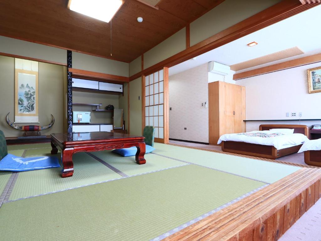- une chambre avec un lit et un banc dans l'établissement Suzunami, à Toba