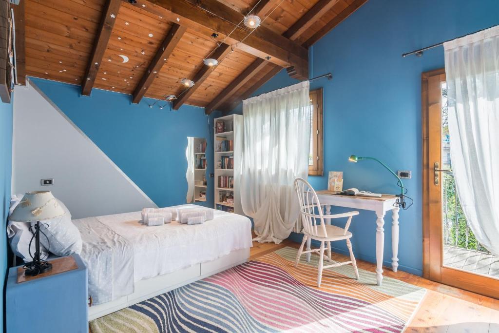 une chambre avec des murs bleus et un lit et un bureau dans l'établissement La Nocciola by PosarelliVillas, à Cereto 27 autres photos