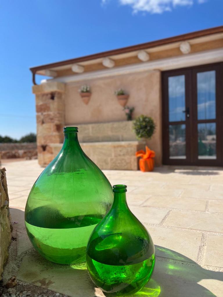 deux vases verts en verre assis devant une maison dans l'établissement I Trulli di Giorgia, à Torre Suda