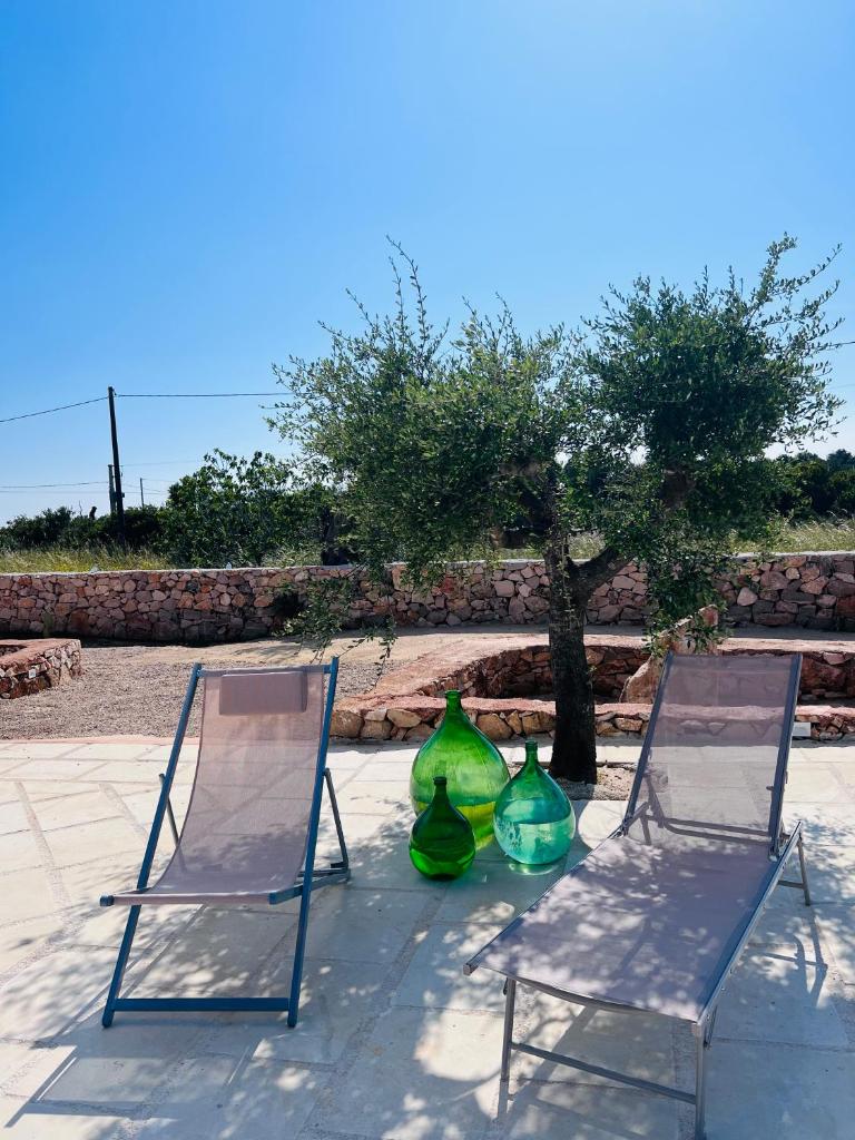 deux chaises et deux vases assis à côté d'un arbre dans l'établissement I Trulli di Giorgia, à Torre Suda 39 autres photos