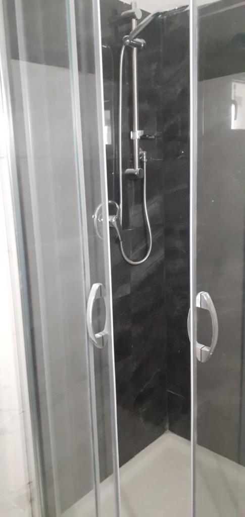 une douche avec une porte vitrée dans une salle de bain dans l'établissement Palazzo Galante, à Margherita di Savoia