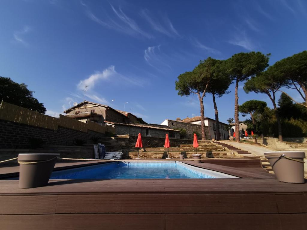 une piscine avec des parasols orange et des arbres dans l'établissement Corte Signoretti - Hystorical Villa, à Canale Monterano