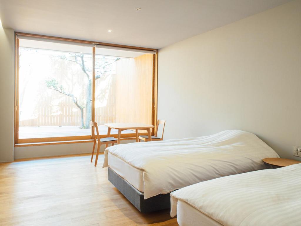une chambre avec deux lits et une table et une fenêtre dans l'établissement Gyokusenkaku, à Nagato