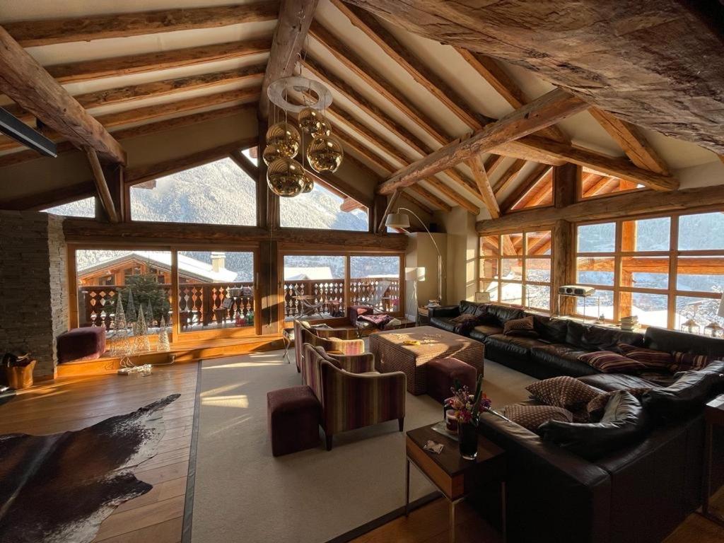 - un grand salon avec des canapés, des tables et des fenêtres dans l'établissement Chalet Violettes, à Villaroger