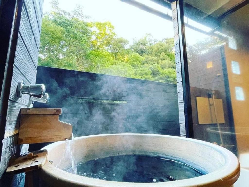 une baignoire dans une salle de bain avec une fenêtre dans l'établissement LiVEMAX RESORT Shizuoka Amagiyugashima, à Izu