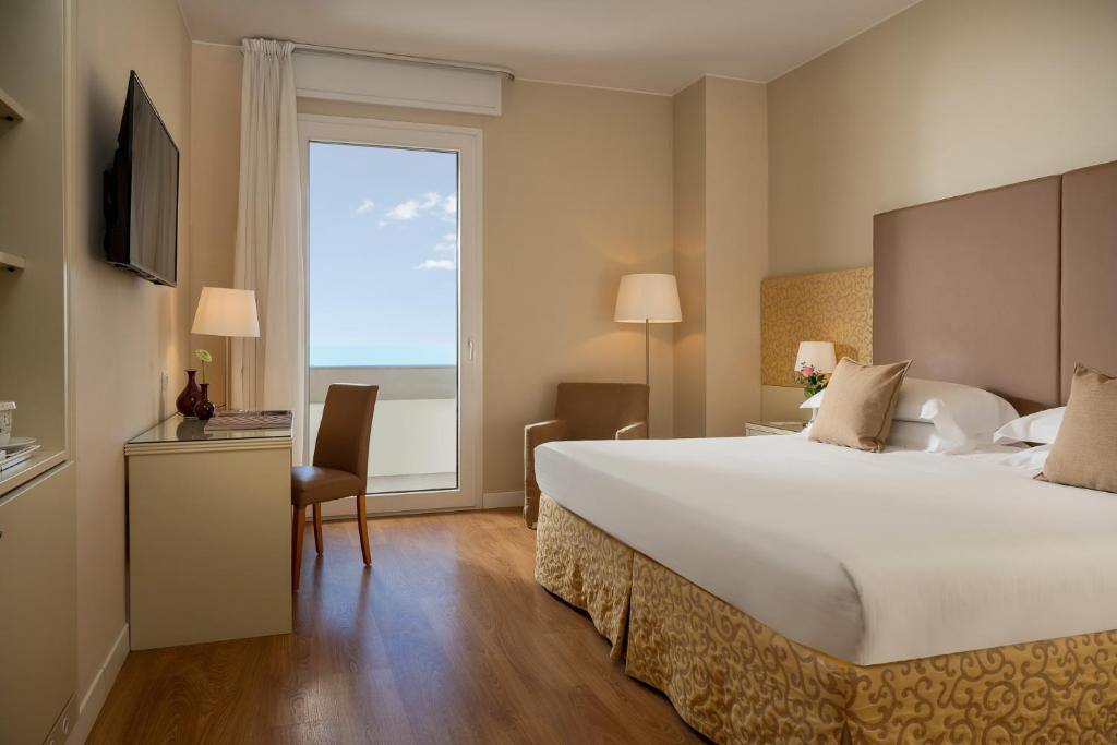 une chambre d'hôtel avec un grand lit blanc et une fenêtre dans l'établissement National Hotel, à Rimini 33 autres photos