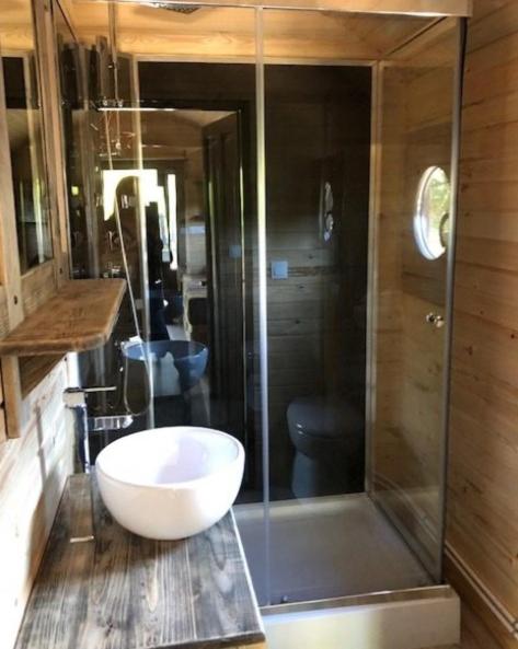 une salle de bain avec une douche en verre et une vasque blanche dans l'établissement Camping Onlycamp du Rouergue, à Villefranche-de-Rouergue