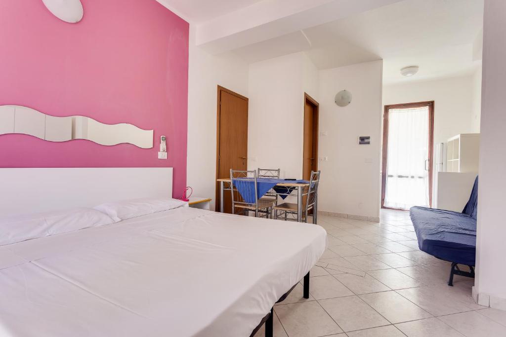 une chambre avec un lit blanc et un mur rose dans l'établissement Residence Blu Marlin Natural free beach, à Lido Adriano