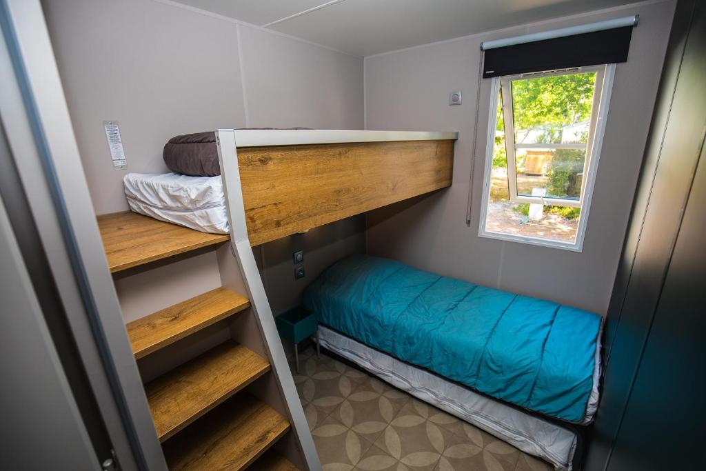 une chambre avec deux lits superposés et une fenêtre dans l'établissement Camping Paradis Carcans Lacanau, à Carcans