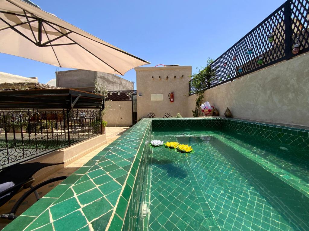 - une piscine avec des fleurs jaunes sur le côté d'un bâtiment dans l'établissement Riad magnolia privé, à Marrakech