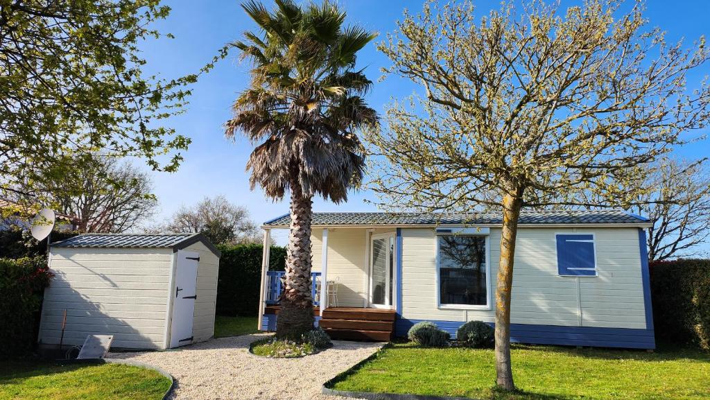 une maison avec un palmier devant dans l'établissement Mobil Home 5 pers 1 Km de l'Océan, à Talmont-Saint-Hilaire