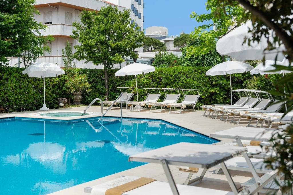 une piscine avec chaises longues et parasols dans l'établissement Hotel Maddalena, à Riccione