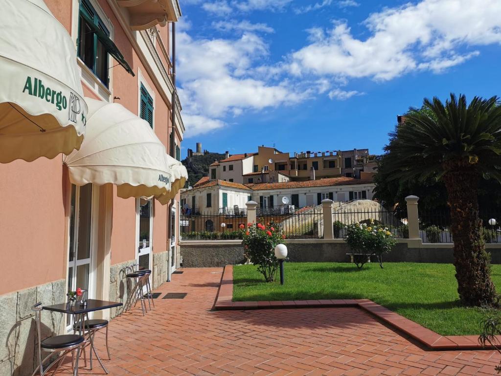 un patio avec tables et chaises et un palmier dans l'établissement Albergo MP Noli, à Noli