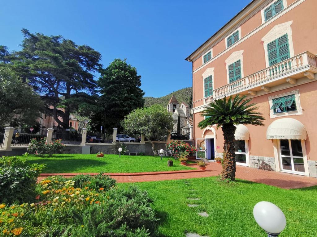 un grand bâtiment rose avec un palmier dans la cour dans l'établissement Albergo MP Noli, à Noli