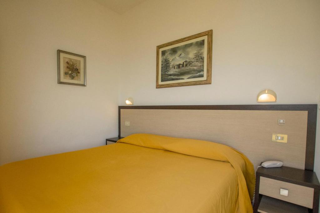 - une chambre avec un lit jaune et deux photos sur le mur dans l'établissement Hotel Apollonia, à Lido di Savio