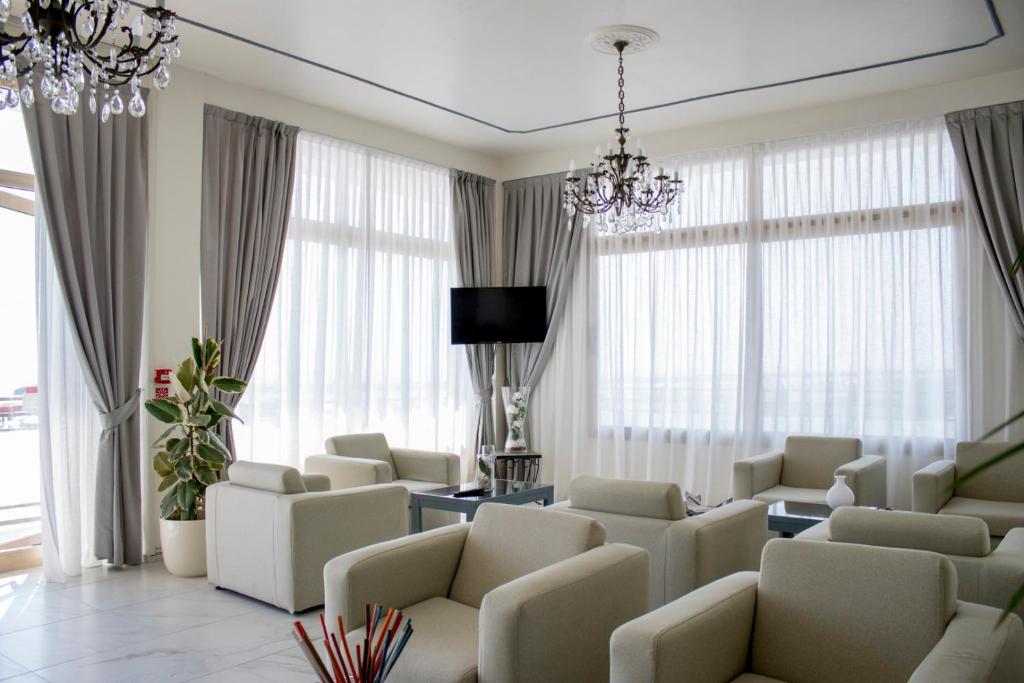 d'un salon avec des chaises blanches et un lustre. dans l'établissement Hotel Apollonia, à Lido di Savio