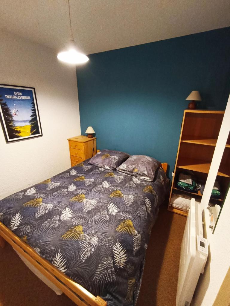 une chambre avec un lit avec un mur bleu dans l'établissement Appartement T2 idéal pour une famille, à Thollon-les-Mémises