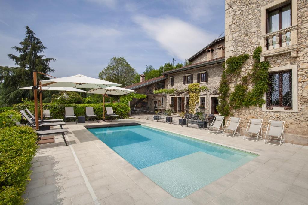 - une piscine avec des chaises et un parasol à côté d'un bâtiment dans l'établissement Villa Sibilla Il Giardino Di Sibilla With Pool, à Monte San Lorenzo
