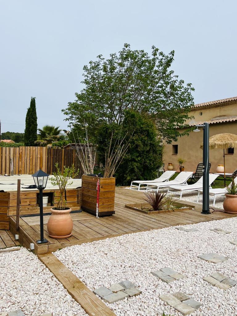 un patio avec un tas de lits sur une terrasse en bois dans l'établissement L Atelier gîte 3 étoiles avec piscine Le Jas des Oliviers, au Castellet