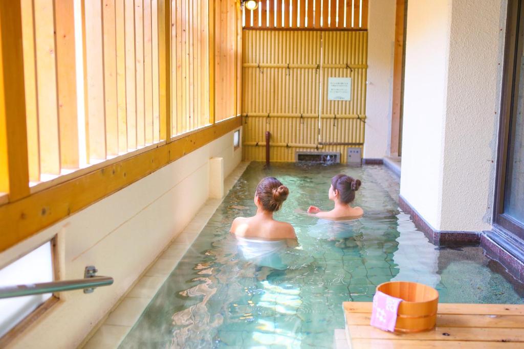 Deux femmes dans l'eau d'une piscine dans l'établissement Ooedo Onsen Monogatari Hotel Shinko, à Fuefuki