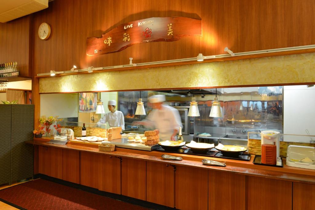 une cuisine avec un chef préparant des plats dans l'établissement Ooedo Onsen Monogatari Hotel Shinko, à Fuefuki