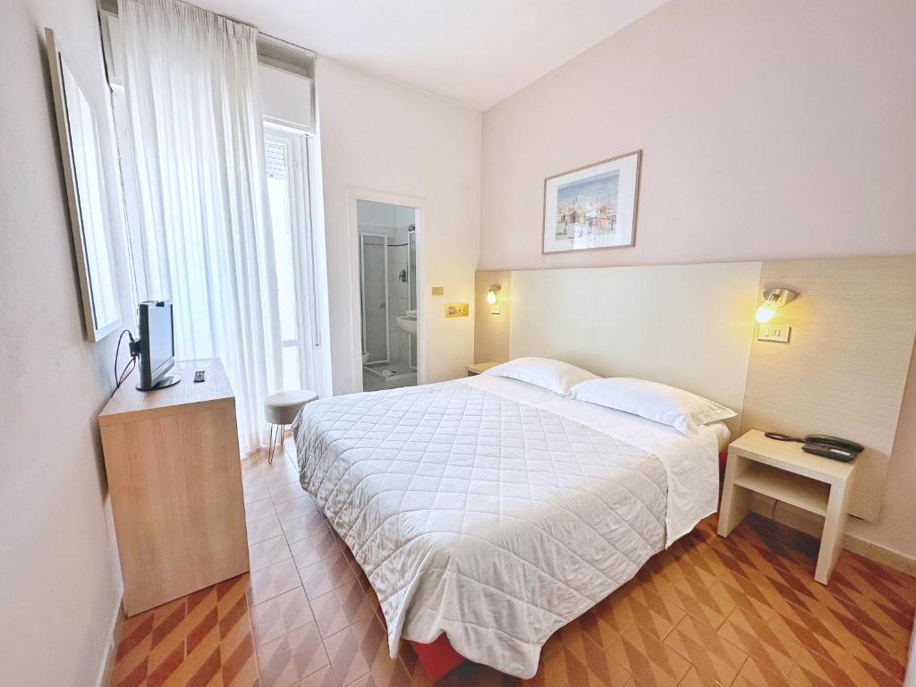 une chambre avec un lit blanc et une télévision dans l'établissement Aura Living Hotel, à Rimini