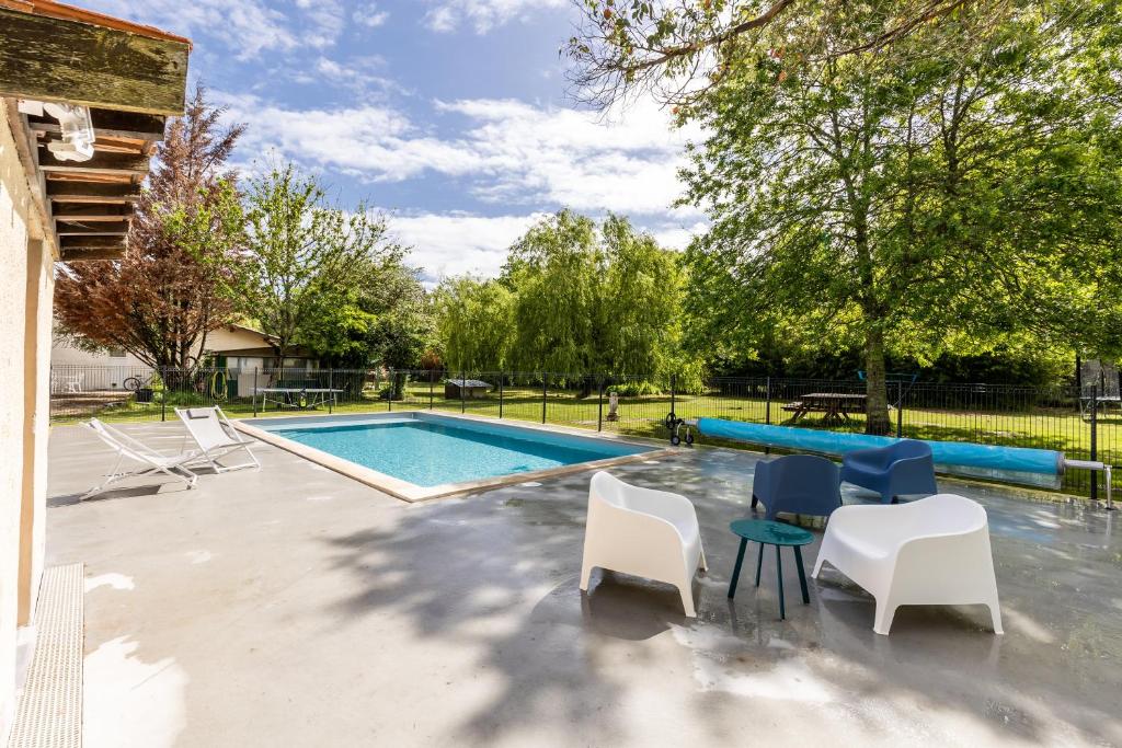 - une piscine avec un groupe de chaises et une table dans l'établissement Gite Senguinous 2, à Lesparre-Médoc