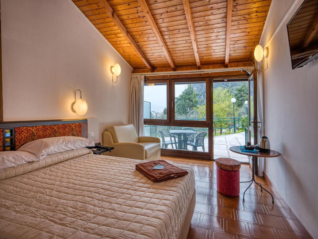 une chambre avec un grand lit et un balcon dans l'établissement Hotel Leonardo Da Vinci, à Limone sul Garda