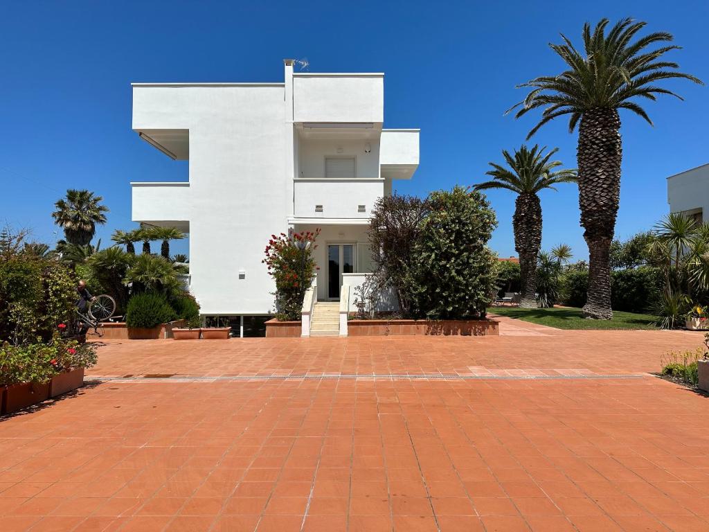 une maison blanche avec des palmiers devant dans l'établissement Villa Antonia sul mare con piscina Torre a mare (Bari), à Bari
