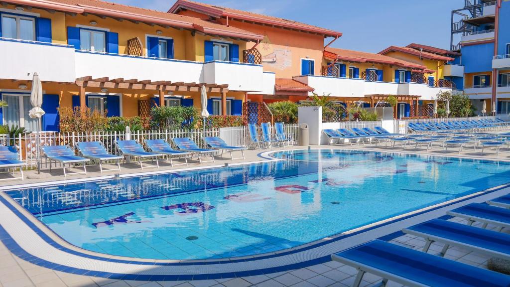 une piscine dans un hôtel avec des chaises bleues dans l'établissement Villaggio Hemingway - Family Aparthotel, à Caorle