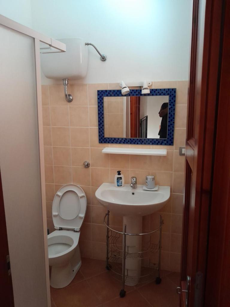 une salle de bain avec toilettes, lavabo et miroir dans l'établissement Villa su due livelli super accessoriata, à SantʼAnna Arresi