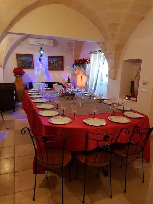 une longue table rouge avec des chaises et des verres à vin dans l'établissement Borgo Guastaferri Villa & Pool !, à Oria 31 autres photos