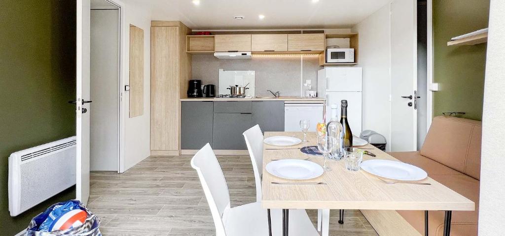Il dispose d'une cuisine et d'une table à manger avec des chaises blanches. dans l'établissement Camping Porto Vecchio, à Porto-Vecchio