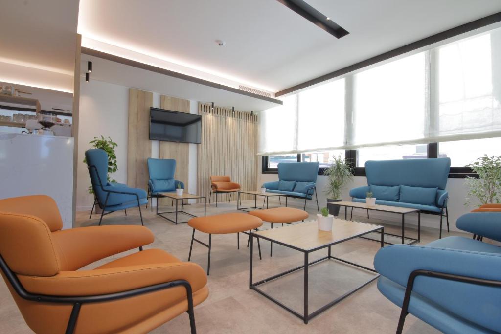 une salle d'attente avec des chaises et des tables bleues et oranges dans l'établissement Hotel Toledo, à Lido di Jesolo