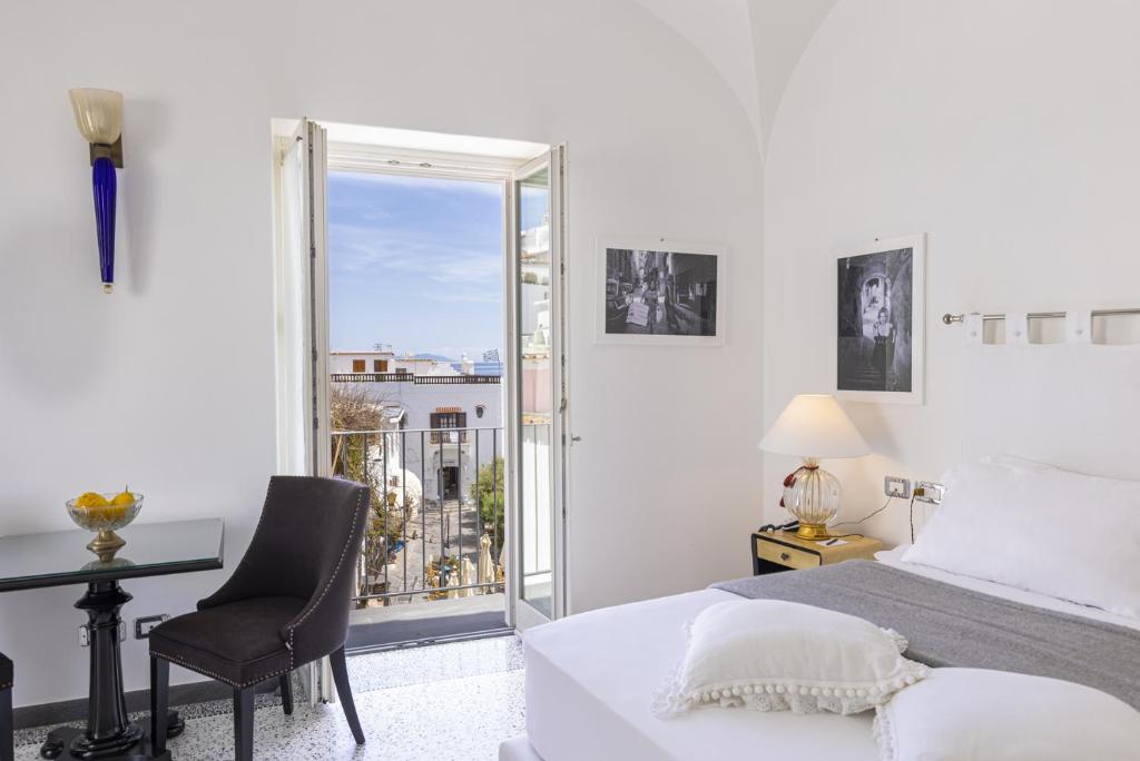 une chambre blanche avec un lit, un bureau et une fenêtre dans l'établissement Roccobarocco Boutique Hotel, à Ischia