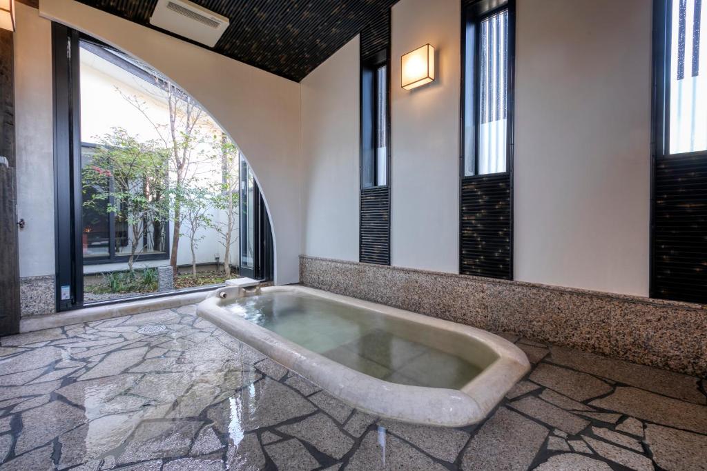 - une baignoire dans une chambre avec fenêtres dans l'établissement Bettei Soan, à Minami Aso