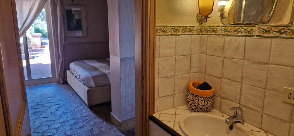 La salle de bains est pourvue d'un lavabo et d'une porte menant à une chambre. dans l'établissement villa favoloso, à Taormine