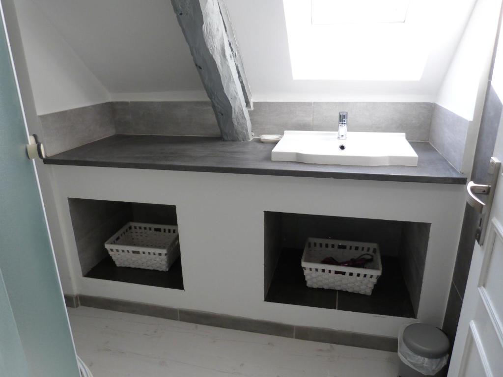 une salle de bain avec un lavabo et des paniers au mur dans l'établissement Gîte avec Piscine proche de St Cirq Lapopie, à Berganty