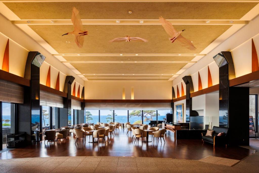 une salle à manger avec des tables, des chaises et des oiseaux au plafond dans l'établissement Hotel Oosado, à Sado