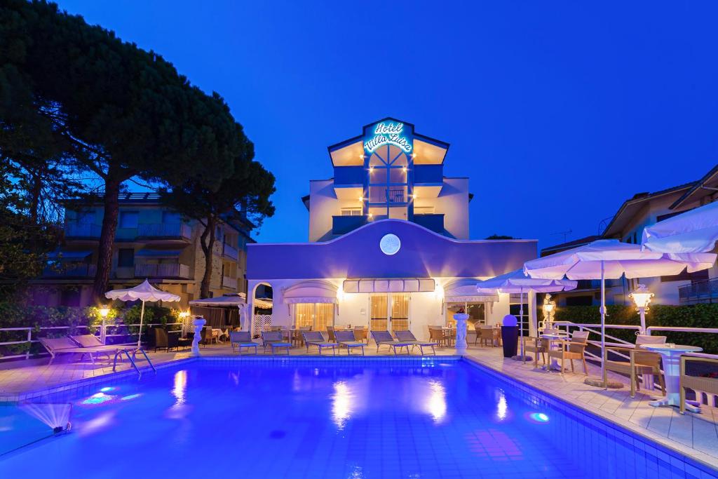 un hôtel avec une piscine devant un bâtiment dans l'établissement Hotel Villa Luisa, à Lignano Sabbiadoro