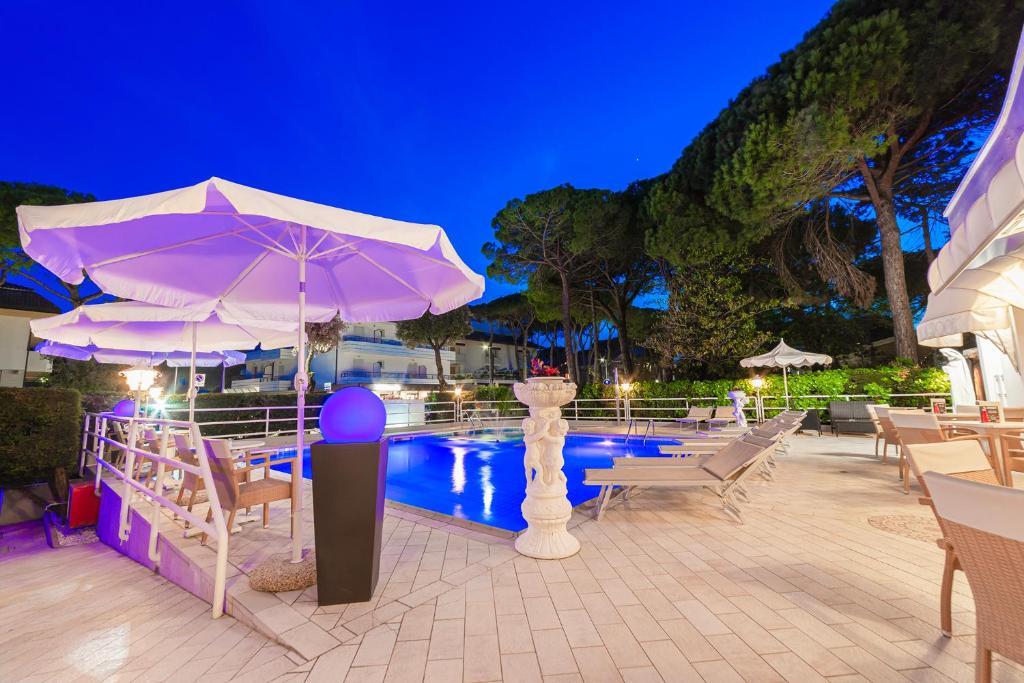 - un billard avec des tables et des chaises ainsi qu'un parasol violet dans l'établissement Hotel Villa Luisa, à Lignano Sabbiadoro