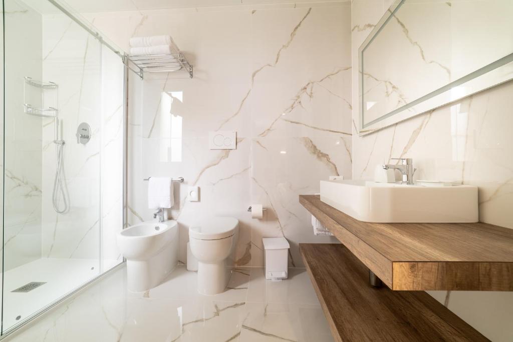 une salle de bain avec un lavabo, des toilettes et une douche dans l'établissement Hotel Colombo, à Lido di Jesolo
