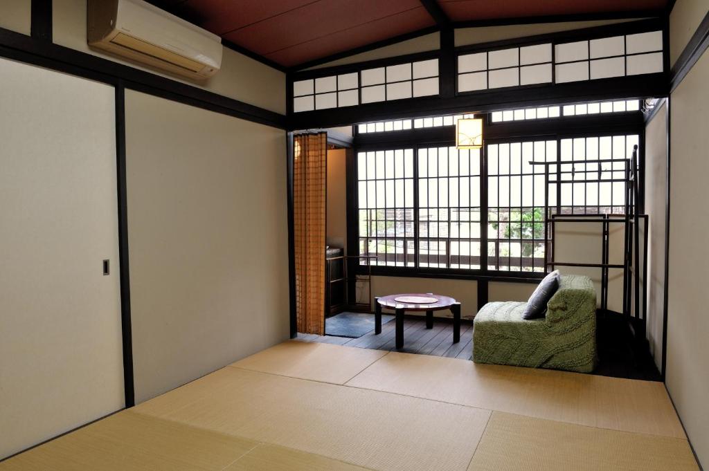 une pièce avec une fenêtre, une chaise et une table dans l'établissement Yadoya Nishijinso, à Kyoto